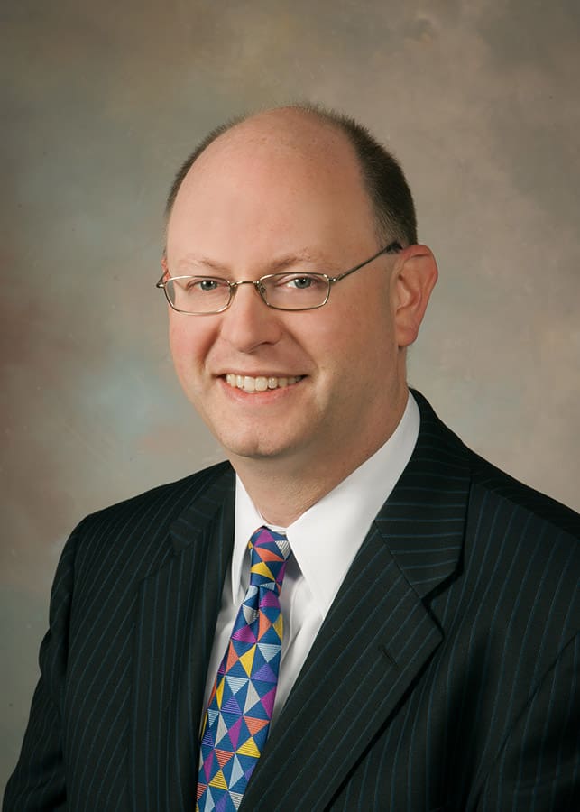 A man in a suit and tie smiling for the camera.