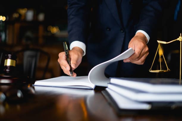 A person in a suit and tie writing on paper.